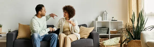 An African American couple sits on a couch, using sign language to communicate, showcasing the beauty of nonverbal communication. — Stock Photo