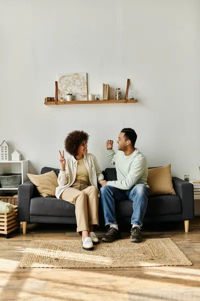 Una coppia afroamericana si siede su un divano nella loro casa, comunicando con il linguaggio dei segni. — Foto stock