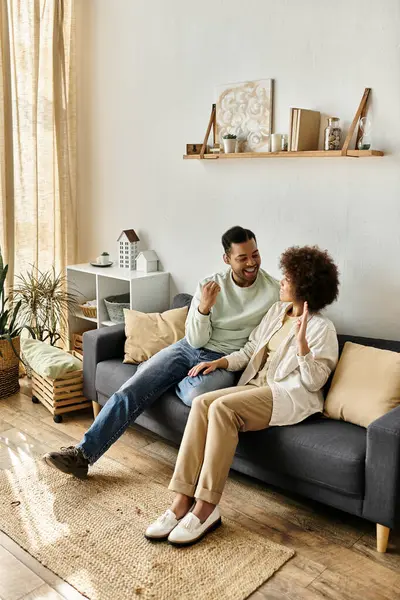 A couple communicates with sign language while sitting on a couch in their home. — Stock Photo