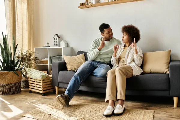 Una coppia si siede su un divano, usando il linguaggio dei segni per comunicare tra loro. — Foto stock