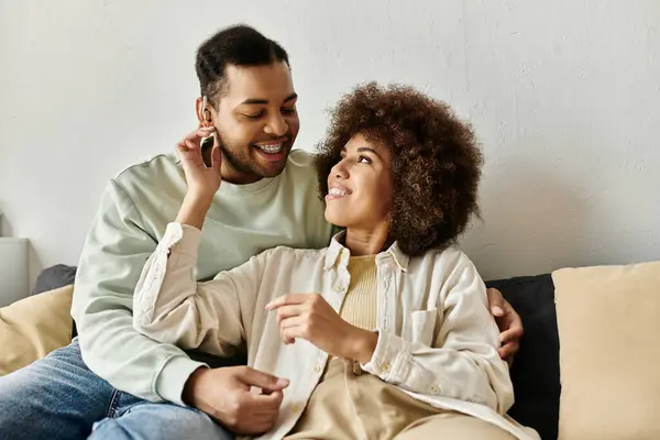 An African American couple sits on a couch at home, communicating in sign language and smiling at each other. — Stock Photo
