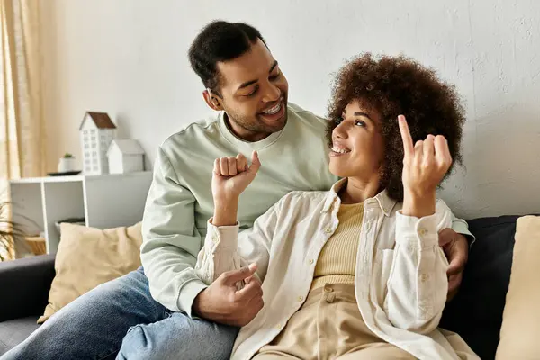 A happy African American couple communicates using sign language while sitting on a couch at home. — Stock Photo