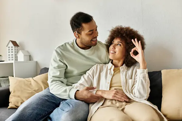 An African American couple sits on a couch at home, communicating with each other through sign language. — Stock Photo