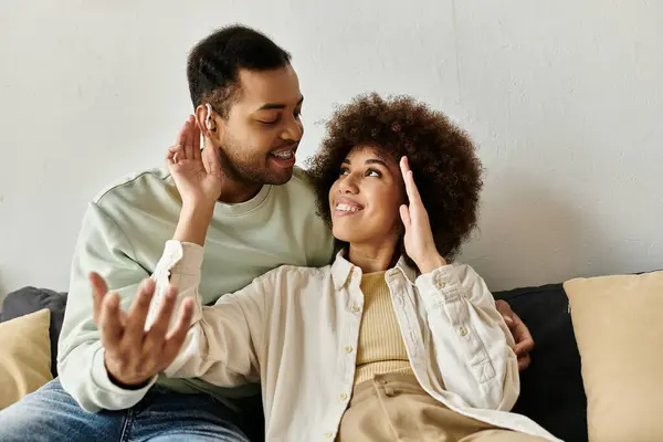 An African American couple uses sign language to communicate while sitting on a couch in their home. — Stock Photo