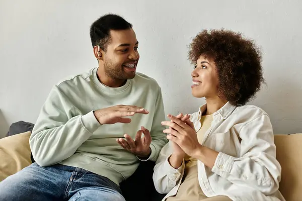 An African American couple communicates through sign language while sitting on a couch at home. — Stock Photo