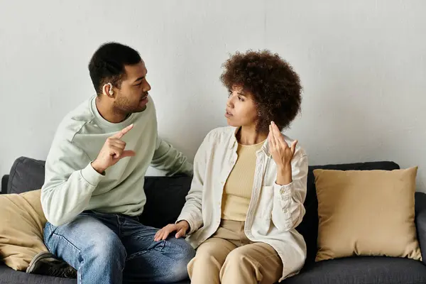 An African American couple sits on a couch, using sign language to communicate. — Stock Photo