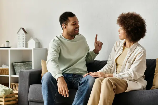 An African American couple sits on a couch, using sign language to communicate. — Stock Photo