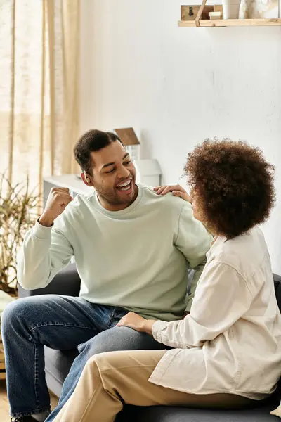 An African American couple uses sign language to communicate while sitting on a couch in their home. — Stock Photo