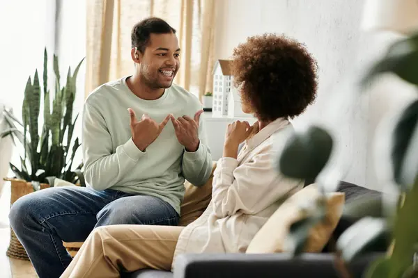 A couple communicates using sign language while sitting on a couch at home. — Stock Photo