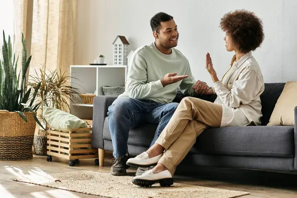 An African American couple sits on a couch in their home, using sign language to communicate. — Stock Photo