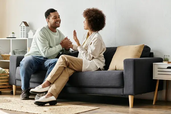 An African American couple sits on a couch in their home, using sign language to communicate. — Stock Photo
