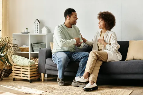 Um casal afro-americano se senta em um sofá em sua casa, se comunicando com a língua de sinais. — Fotografia de Stock