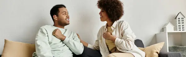 An African American couple sits on a couch, communicating with sign language. — Stock Photo