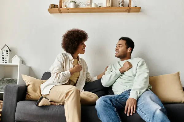 Una pareja se sienta en un sofá y conversa usando lenguaje de señas. - foto de stock