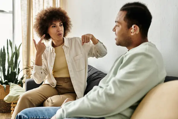 An African American couple sits on a couch, communicating with sign language. — Stock Photo