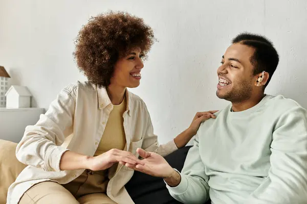 An African American couple communicates in sign language while sitting on a couch at home. — Stock Photo