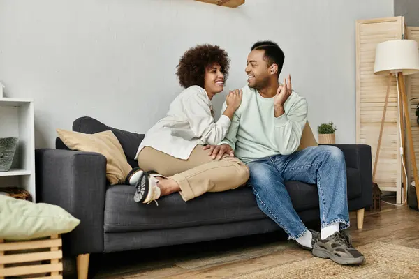 Un couple afro-américain utilise la langue des signes pour communiquer assis sur un canapé dans leur maison. — Photo de stock