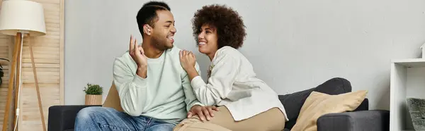 A young African American couple uses sign language to communicate while relaxing on a couch at home. — Stock Photo