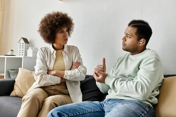 An African American couple uses sign language to communicate while sitting on a couch. — Stock Photo