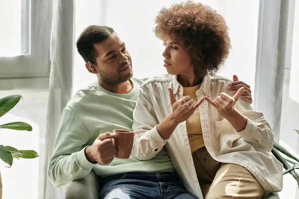 Um casal afro-americano usa a linguagem gestual para se comunicar enquanto estão sentados juntos em casa. — Fotografia de Stock
