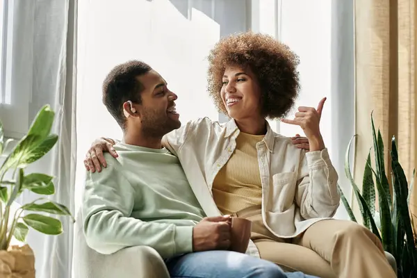 Una bella coppia afroamericana si siede su un divano, usando il linguaggio dei segni per comunicare tra loro. — Foto stock