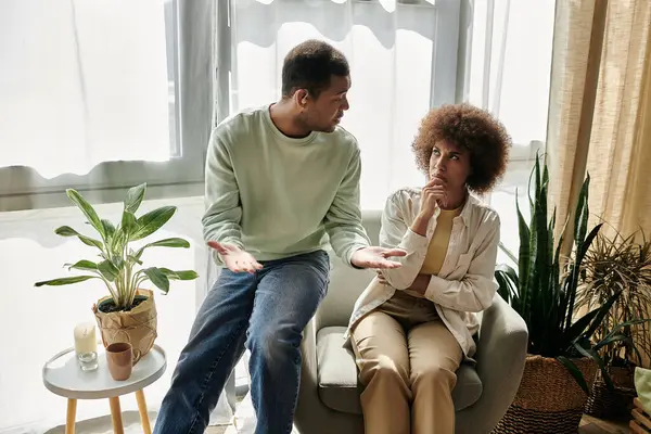 An attractive African American couple sits in their living room, using sign language to communicate. — Stock Photo