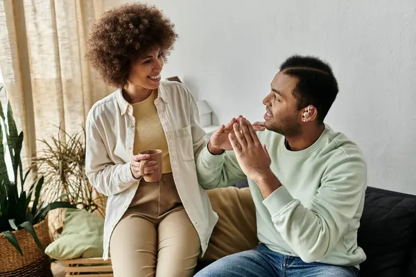 Um casal afro-americano se comunica através da língua de sinais enquanto desfruta de um momento aconchegante em casa. — Fotografia de Stock