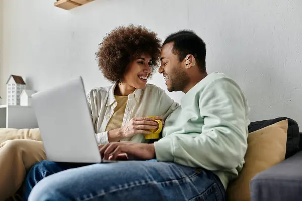 Pretty African American woman sitting near her husband with hearing aid and looking at laptop. — Stock Photo