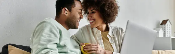 Mulher afro-americana alegre sentado perto de seu marido com aparelho auditivo e olhando para laptop. — Fotografia de Stock