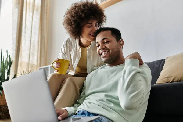 Loving African American woman sitting near her husband with hearing aid and looking at laptop. — Stock Photo