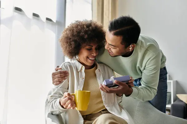 Bella donna afroamericana vicino al marito con apparecchi acustici, regalo in mano. — Foto stock