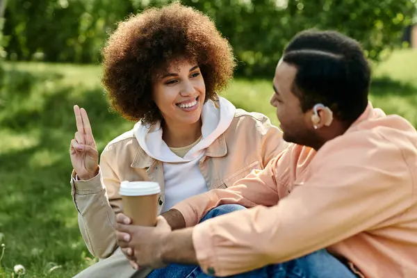 Um casal afro-americano se comunica através da linguagem gestual enquanto se sentam juntos em um parque. — Fotografia de Stock