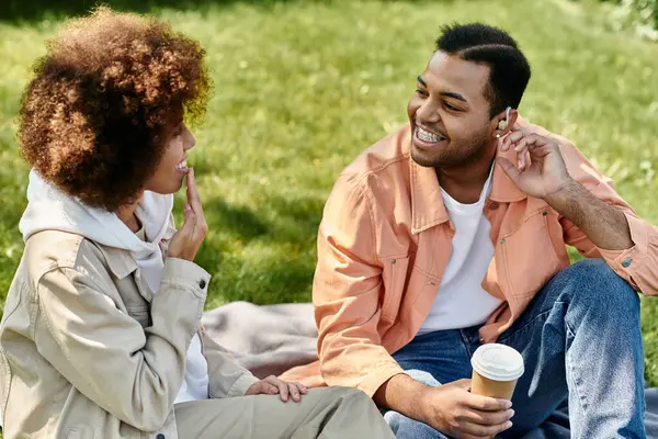 An African American couple sits on a blanket in a park, using sign language to communicate. — Stock Photo