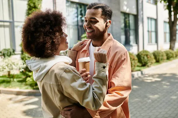 An African American couple smiles and signs to each other in a city setting. — Stock Photo