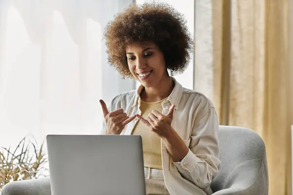 Eine Frau unterschreibt lächelnd, während sie in einem Home Office an ihrem Laptop sitzt. — Stockfoto