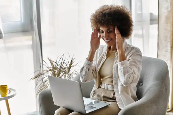A woman sitting on a couch at home, using sign language while looking at a laptop. — Stock Photo