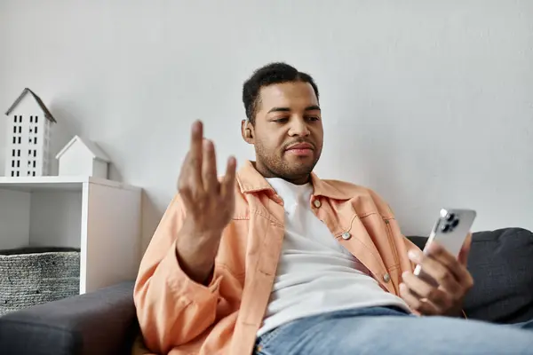 An African American man communicates through sign language while relaxing on a couch at home. — Stock Photo