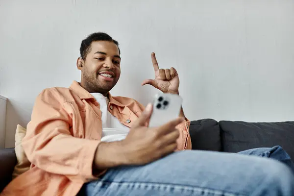 A man communicates using sign language while sitting on a couch. — Stock Photo