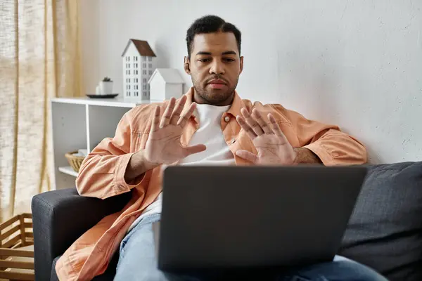 A man signs to laptop while sitting on a couch. — Stock Photo
