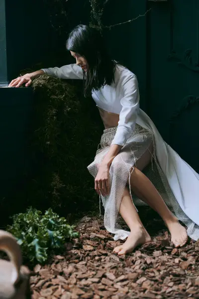 Una mujer vestida de blanco posa cerca de un pantano. - foto de stock
