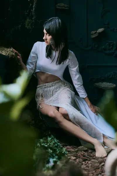 Una mujer en un vestido blanco que fluye posa cerca de un pantano. - foto de stock