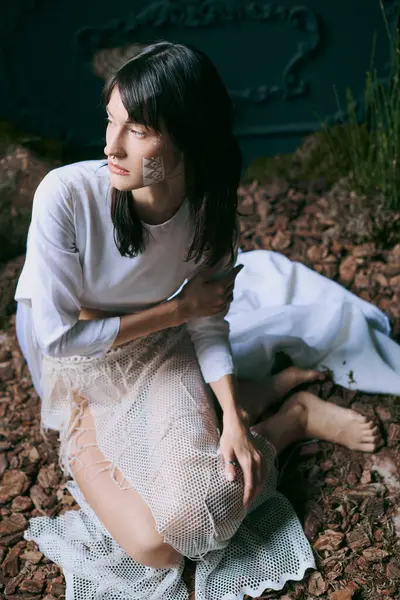 A woman in a white dress sits in a swampy area, looking contemplative. — Stock Photo