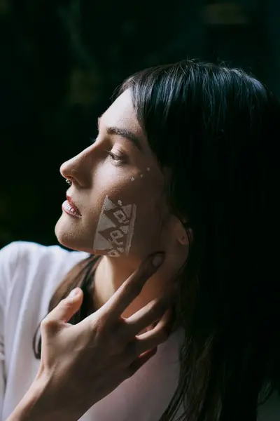 A woman with painted facial art poses against a dark background, near a swamp. — Stock Photo