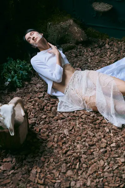 A woman in white clothing poses on ground near swamp. — Stock Photo