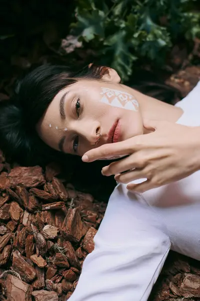 A woman with a white face design poses on ground. — Stock Photo