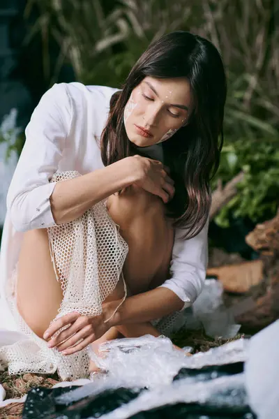 Жінка в білому одязі позує біля болота, наповненого пластиковим сміттям. — стокове фото