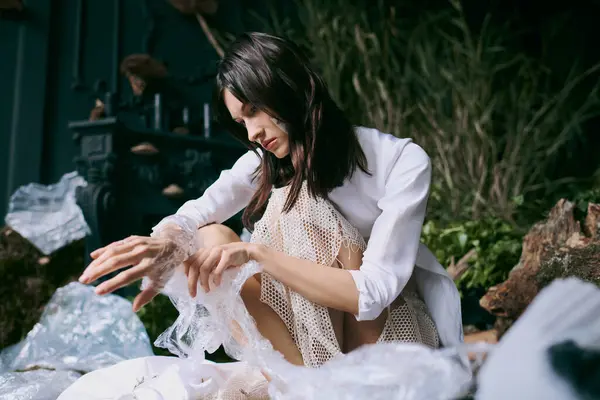 Woman in white shirt and lacy skirt amid plastic in swamp. — Stock Photo