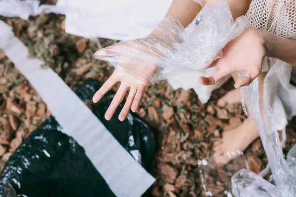 A womans hand emerges from a pile of plastic waste, with only her hand visible. — Stock Photo