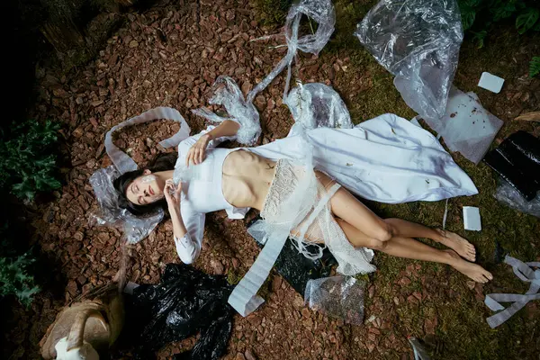 A woman in white clothing poses amidst a swamp filled with plastic garbage. — Stock Photo