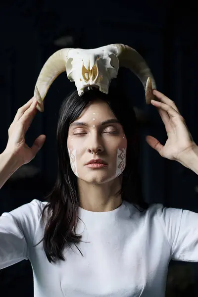 A woman with a skull on her head poses solemnly in front of a swamp. — Stock Photo